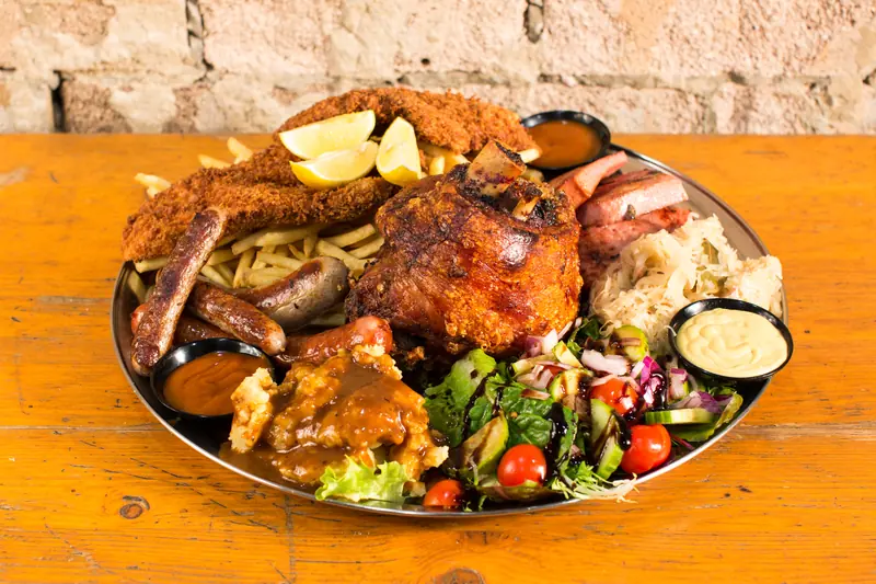 A heaped platter of German specialties with roast chicken, sausages, sauerkraut and salad