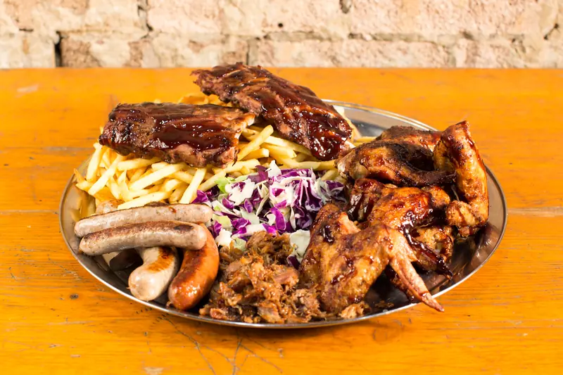 Barbecue platter of smoked pork ribs, chicken wings, pulled pork, sausages and chips