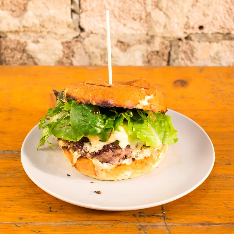 Beef burger with lettuce and aioli on a plate on a timber table