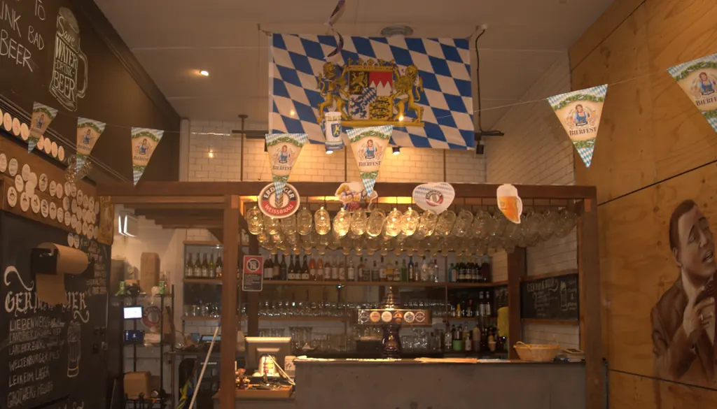 Inside Mia’s Cronulla German Beerhall: the bar with a Bavarian flag hanging above, timber walls and beer signs