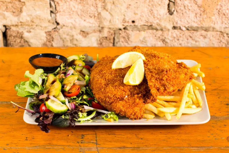Golden crumbed schnitzel with lemon, chips and garden salad